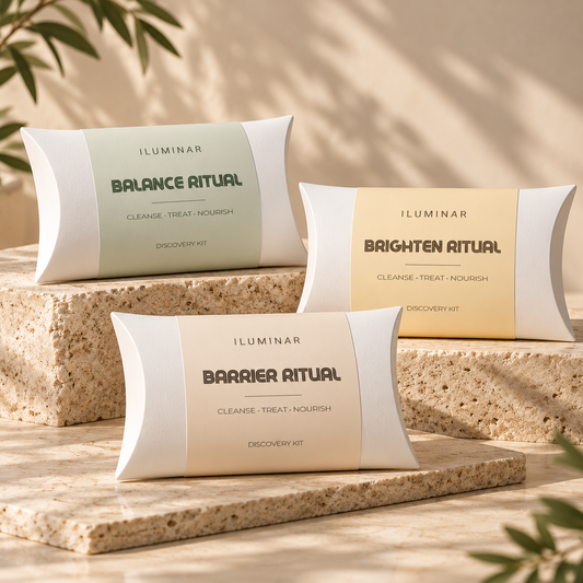 Three ILUMINAR discovery kits in white pillow-style boxes labeled Balance Ritual, Brighten Ritual, and Barrier Ritual, arranged on stone blocks against a warm beige background with soft leaf shadows.